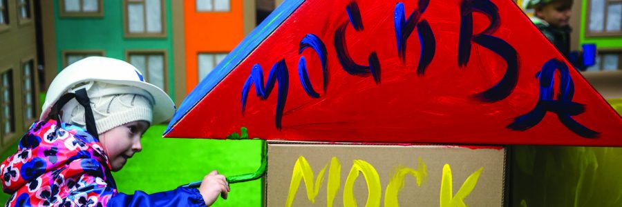 Дети раскрашивают дома красками из картона на площадке фестиваля "Яркие люди" на Неглинной улице в День города Москвы, Россия
