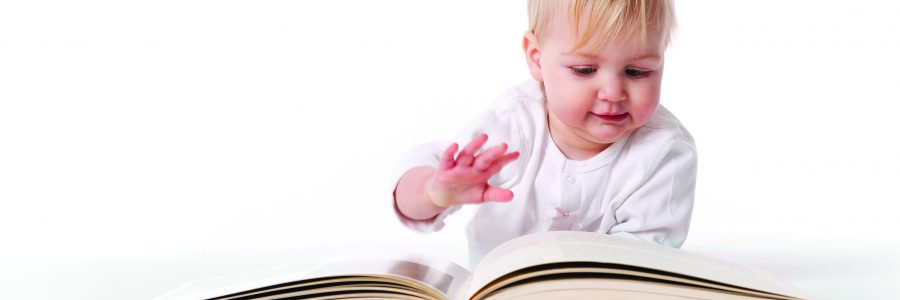Baby Girl Is Pretending To Read A Large Book On White Background