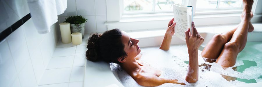 Woman reading book in bubble bath