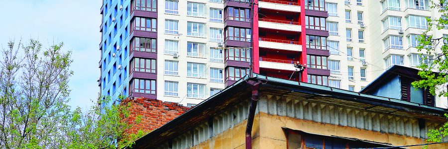 Город растет. Фрагмент старого ветхого жилого дома на фоне новостройки