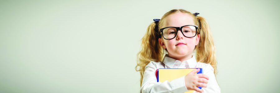 Schoolgirl in glasses reaching toward the school.