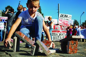 Мальчик строит дома из облицовочной гранитной плитки во время митинга обманутых дольщиков строительной компании СУ-155 на Суворовской площади города Москвы, Россия, 26 сентября 2015