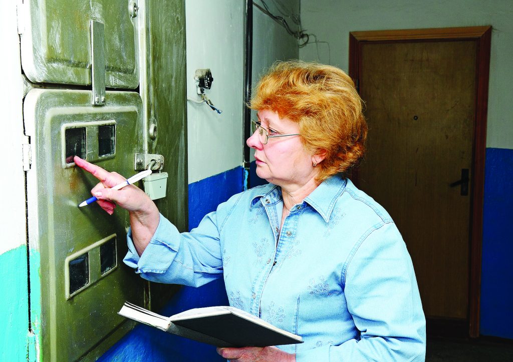 Женщина снимает показания квартирного электросчетчика